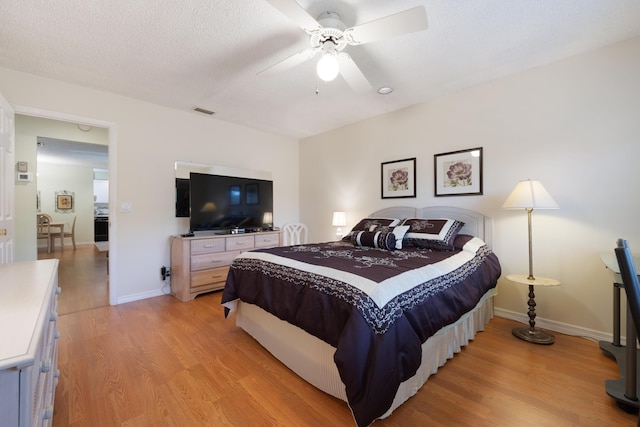 bedroom featuring ceiling fan, light hardwood / wood-style floors, and a textured ceiling