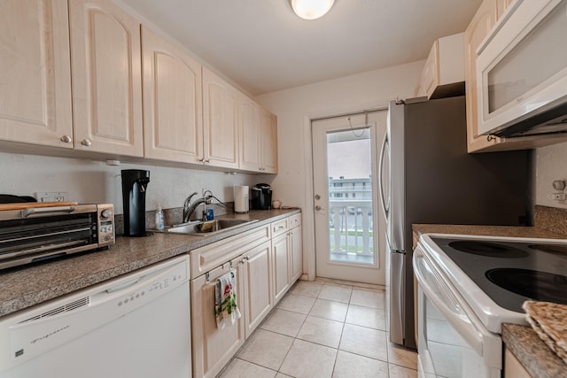 kitchen featuring sink, light tile patterned floors, and white appliances