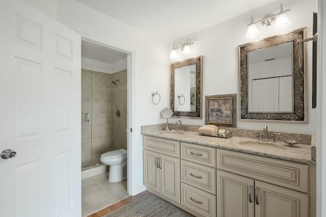 bathroom with hardwood / wood-style floors, vanity, toilet, and a shower with shower door