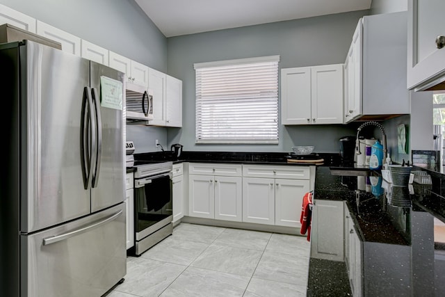 kitchen with sink, stainless steel appliances, white cabinetry, and dark stone countertops