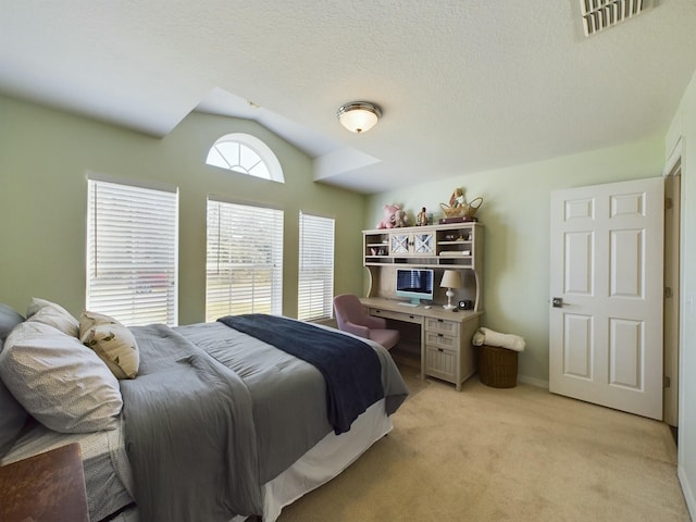 bedroom featuring a textured ceiling, light colored carpet, and vaulted ceiling