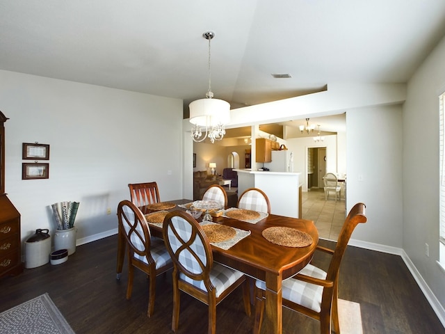 dining area featuring lofted ceiling, dark wood-type flooring, and an inviting chandelier