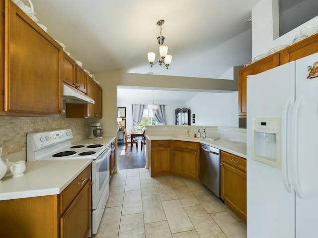 kitchen with a notable chandelier, kitchen peninsula, vaulted ceiling, decorative light fixtures, and white appliances