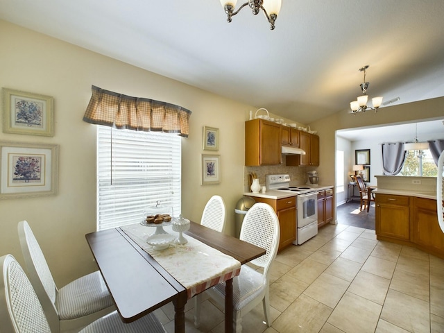 dining space featuring light tile patterned floors, vaulted ceiling, and a notable chandelier