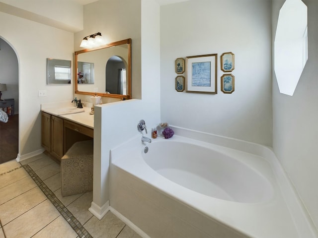 bathroom with tile patterned flooring, a relaxing tiled tub, and vanity