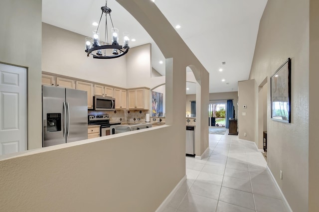 kitchen featuring an inviting chandelier, backsplash, light brown cabinetry, light tile patterned floors, and appliances with stainless steel finishes