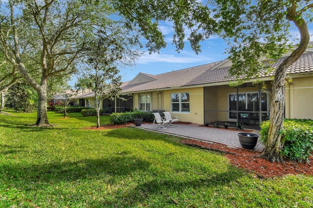 9383 Bridgeport Dr, West Palm Beach, FL 33411 - rear view of property with stucco siding, a yard, a patio, a tiled roof, and a sunroom