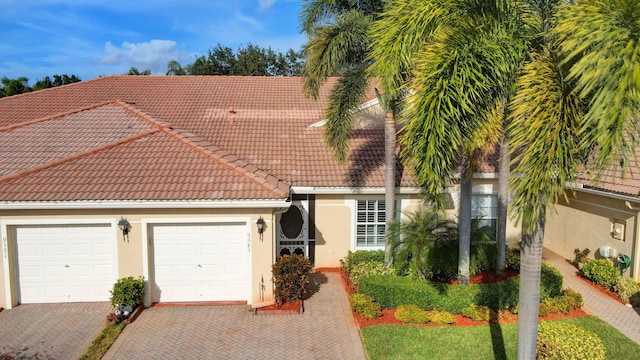 9383 Bridgeport Dr, West Palm Beach, FL 33411 - view of front of home featuring a tile roof, stucco siding, decorative driveway, and a garage