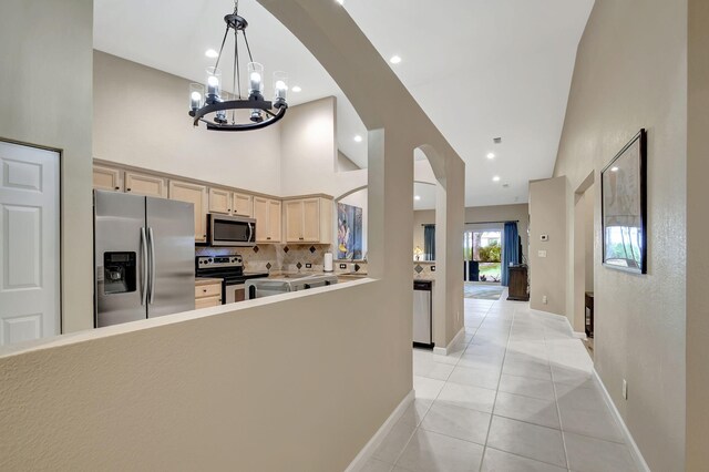 kitchen with sink, stainless steel appliances, light stone counters, decorative backsplash, and light brown cabinets