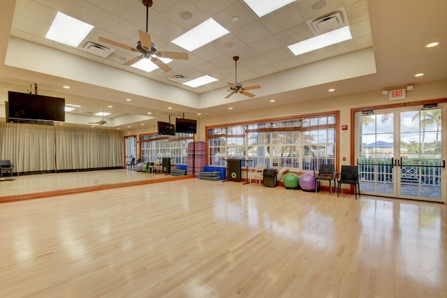 workout room with a tray ceiling, ceiling fan, and hardwood / wood-style flooring