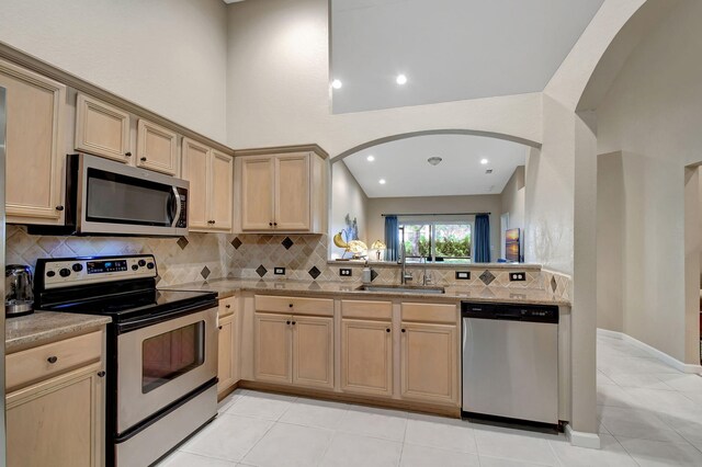 kitchen with sink, light tile patterned floors, appliances with stainless steel finishes, decorative backsplash, and light brown cabinets