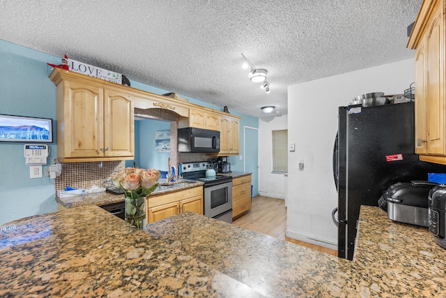 kitchen featuring black appliances, a textured ceiling, light brown cabinetry, tasteful backsplash, and light hardwood / wood-style floors