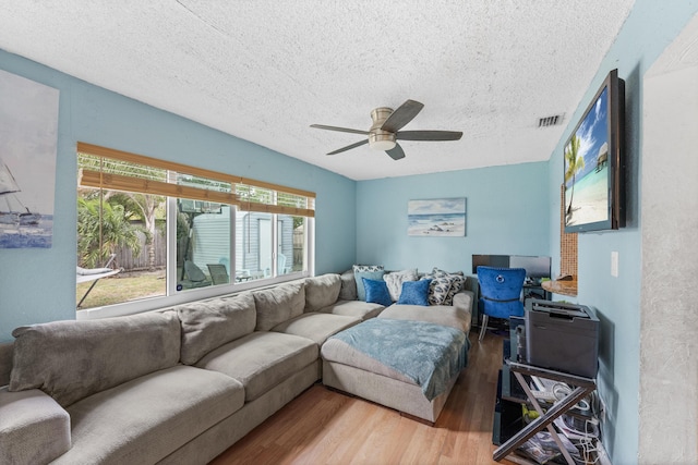 living room with hardwood / wood-style flooring, ceiling fan, and a textured ceiling