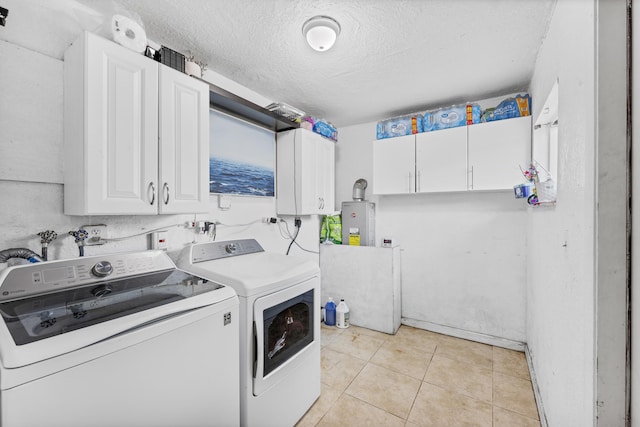 laundry room featuring cabinets, washing machine and dryer, water heater, a textured ceiling, and light tile patterned floors