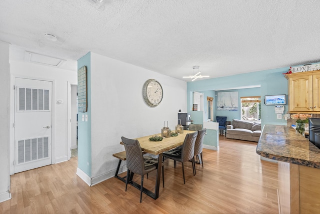 dining room with light hardwood / wood-style flooring and a textured ceiling