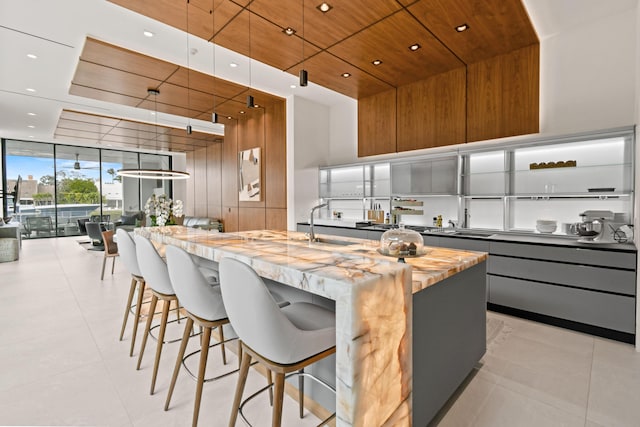 kitchen with an island with sink, modern cabinets, a kitchen bar, and wooden ceiling