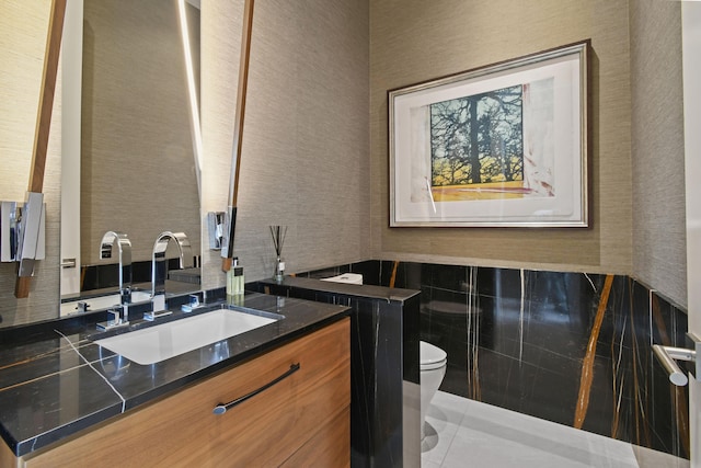 bathroom with vanity, tile walls, and toilet