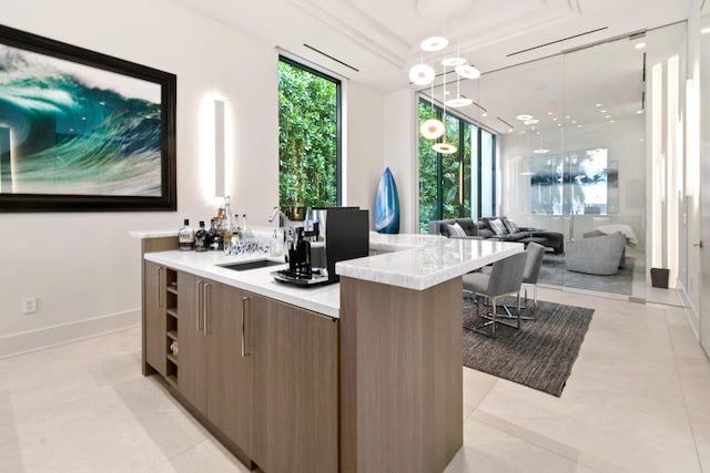 bar featuring a tray ceiling, light tile patterned floors, a sink, a bar, and baseboards