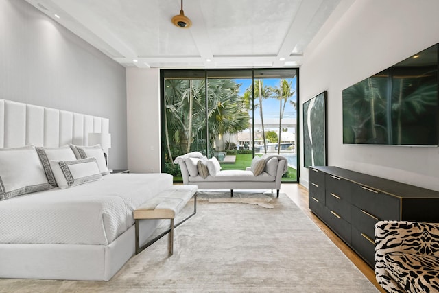 bedroom featuring light wood-style floors, access to exterior, and floor to ceiling windows