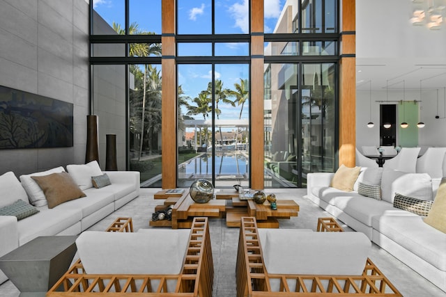 sunken living room with a water view, a towering ceiling, and floor to ceiling windows