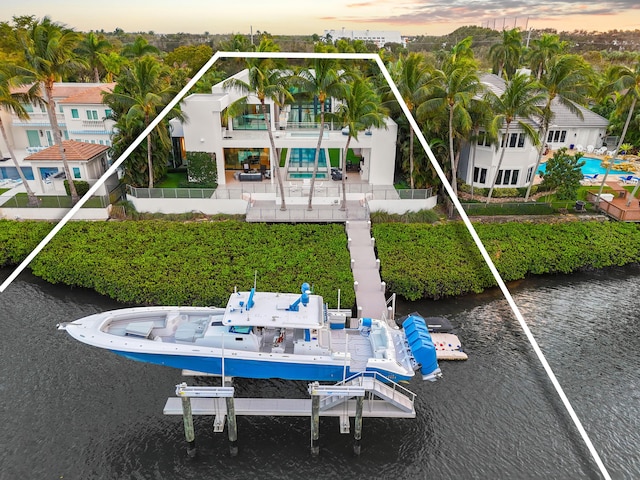 back of property with a water view, a balcony, and fence private yard