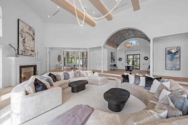 living room featuring beam ceiling, a tile fireplace, high vaulted ceiling, and wood ceiling