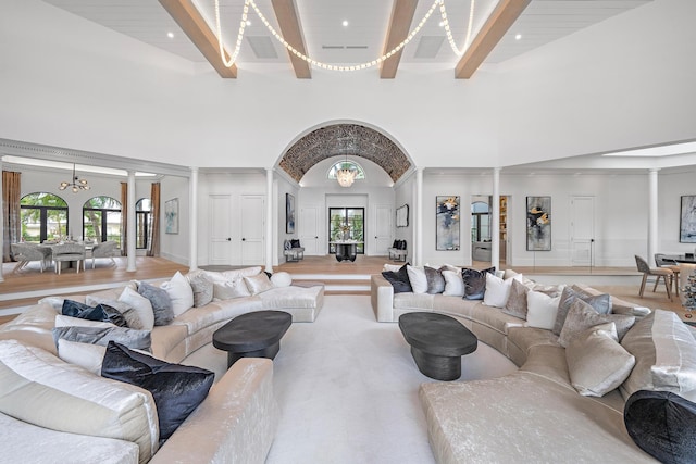 living room with beamed ceiling, high vaulted ceiling, a chandelier, and light hardwood / wood-style floors