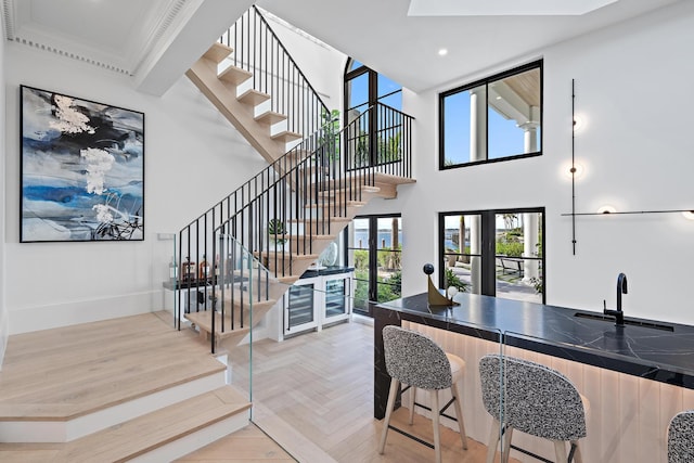 staircase with parquet floors, a towering ceiling, wine cooler, and indoor wet bar