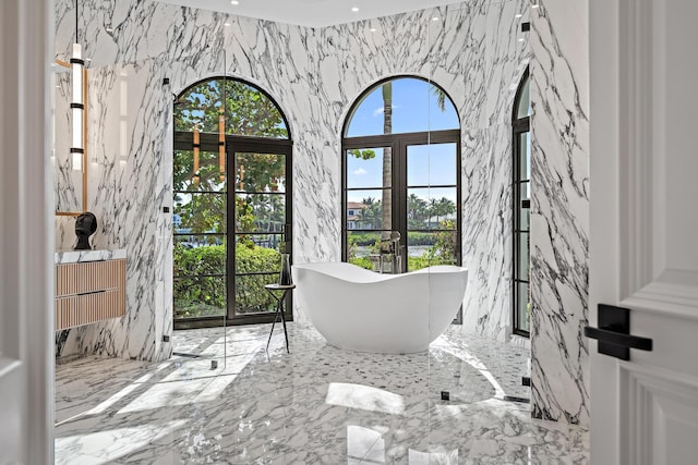 bathroom with vanity, a bath, and french doors