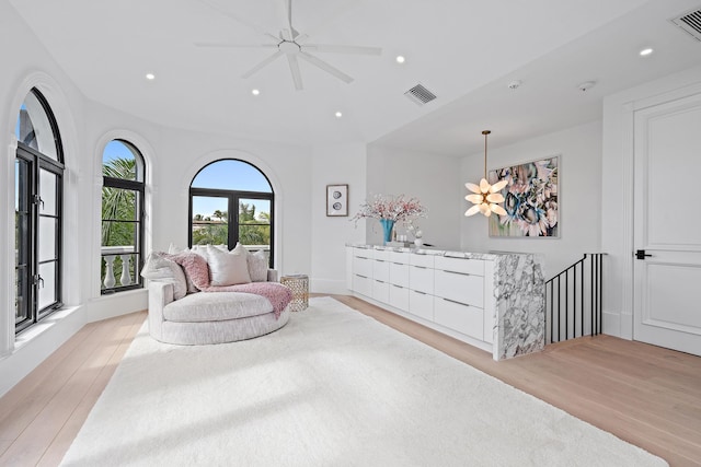 bedroom with light hardwood / wood-style floors and ceiling fan with notable chandelier