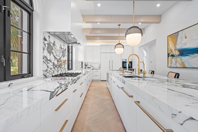 kitchen with light stone countertops, light parquet flooring, white cabinetry, and hanging light fixtures