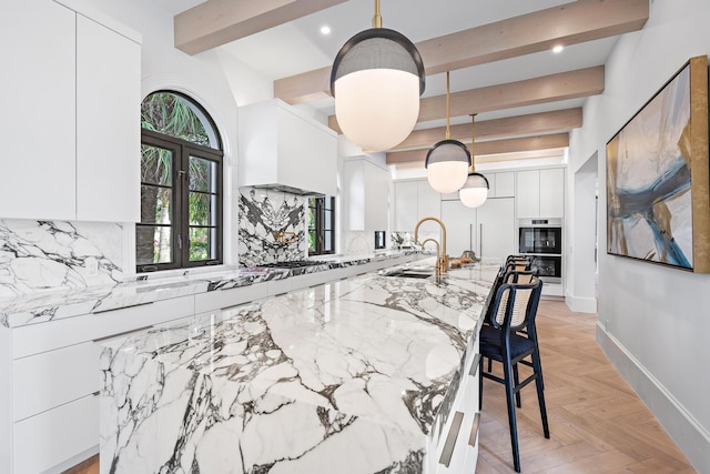 kitchen featuring a kitchen bar, french doors, light stone counters, decorative light fixtures, and white cabinets