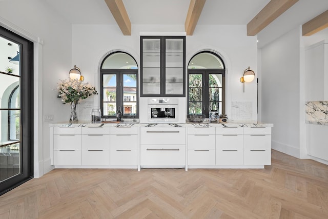 interior space with light stone countertops, french doors, plenty of natural light, and beam ceiling