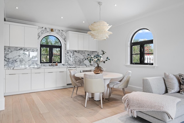 dining room with light hardwood / wood-style floors, ornamental molding, and sink