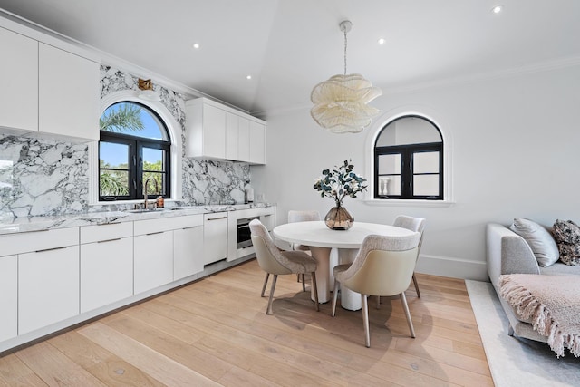 kitchen with pendant lighting, light wood-type flooring, white cabinetry, and ornamental molding