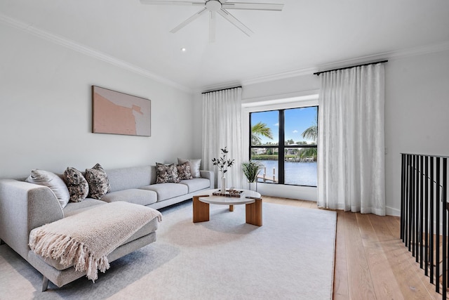 living room featuring ceiling fan, light hardwood / wood-style flooring, a water view, and ornamental molding