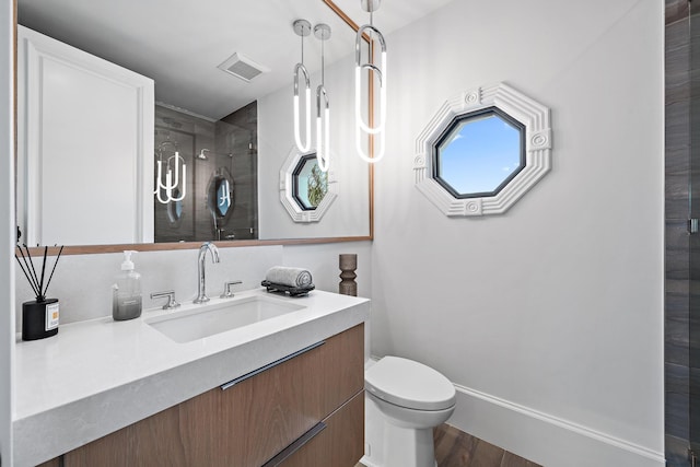 bathroom with hardwood / wood-style floors, vanity, toilet, and a shower with shower door