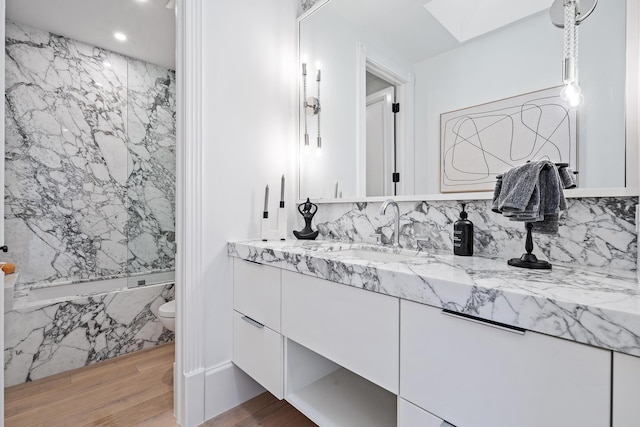 bathroom with hardwood / wood-style floors, vanity, and a skylight