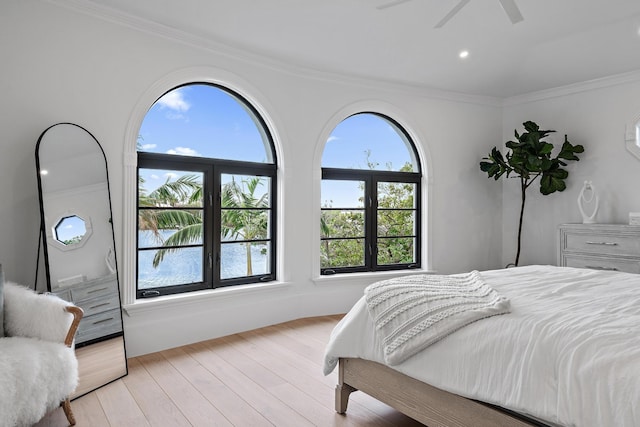 bedroom featuring ceiling fan, light wood-type flooring, ornamental molding, and multiple windows