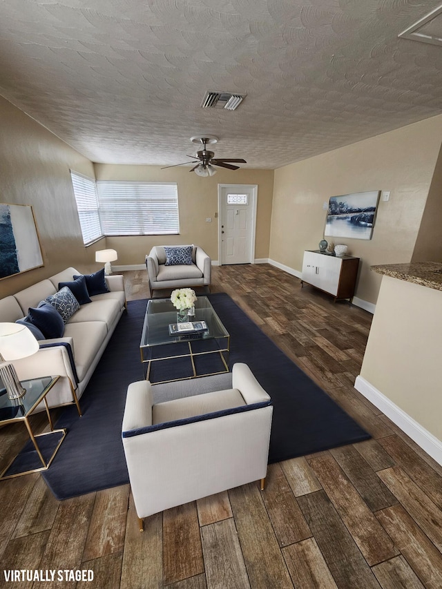 living room featuring a textured ceiling, ceiling fan, and dark wood-type flooring