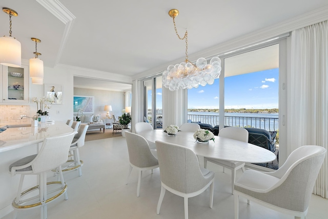 dining room featuring a notable chandelier, a water view, and ornamental molding