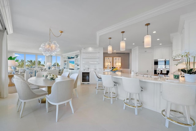 dining space featuring sink, an inviting chandelier, beverage cooler, and ornamental molding