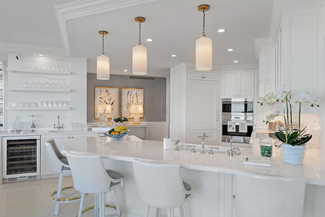 kitchen with white cabinets, pendant lighting, stainless steel double oven, and beverage cooler