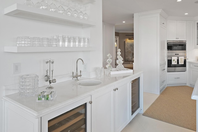 bar with white cabinetry, sink, wine cooler, double oven, and ornamental molding