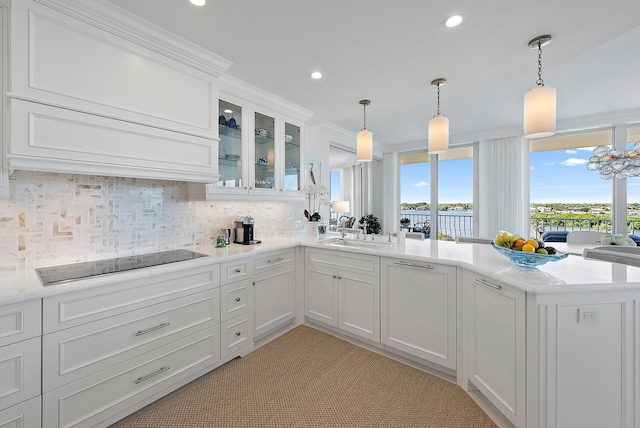 kitchen with kitchen peninsula, black electric stovetop, hanging light fixtures, and sink