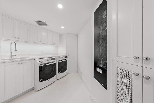 laundry area featuring separate washer and dryer, sink, and cabinets