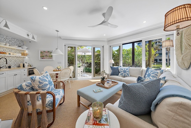 living room featuring ceiling fan, light colored carpet, crown molding, and bar