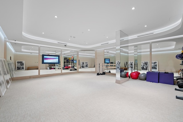 workout area featuring light carpet and a tray ceiling