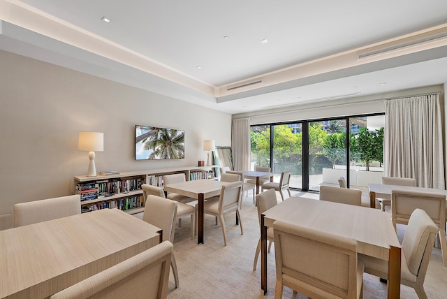 carpeted dining space featuring a raised ceiling