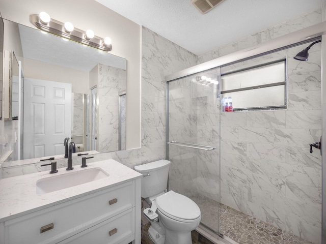 bathroom featuring vanity, toilet, a shower with door, and a textured ceiling